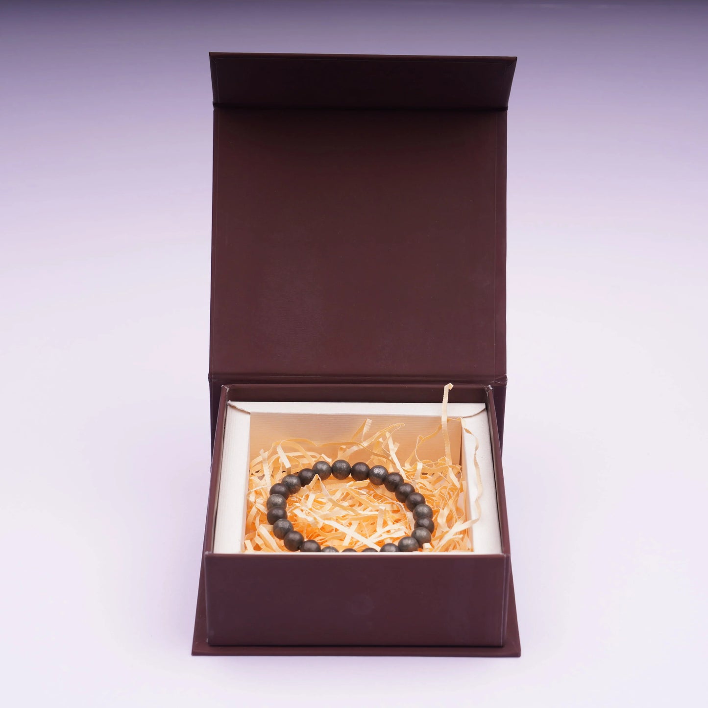 Raw pyrite beaded bracelet in a gift box with shredded paper filling, jewelry product display.