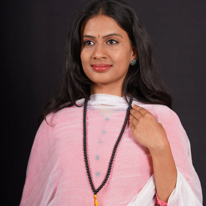 Woman in pink kurta wearing long black beaded mala necklace on black background