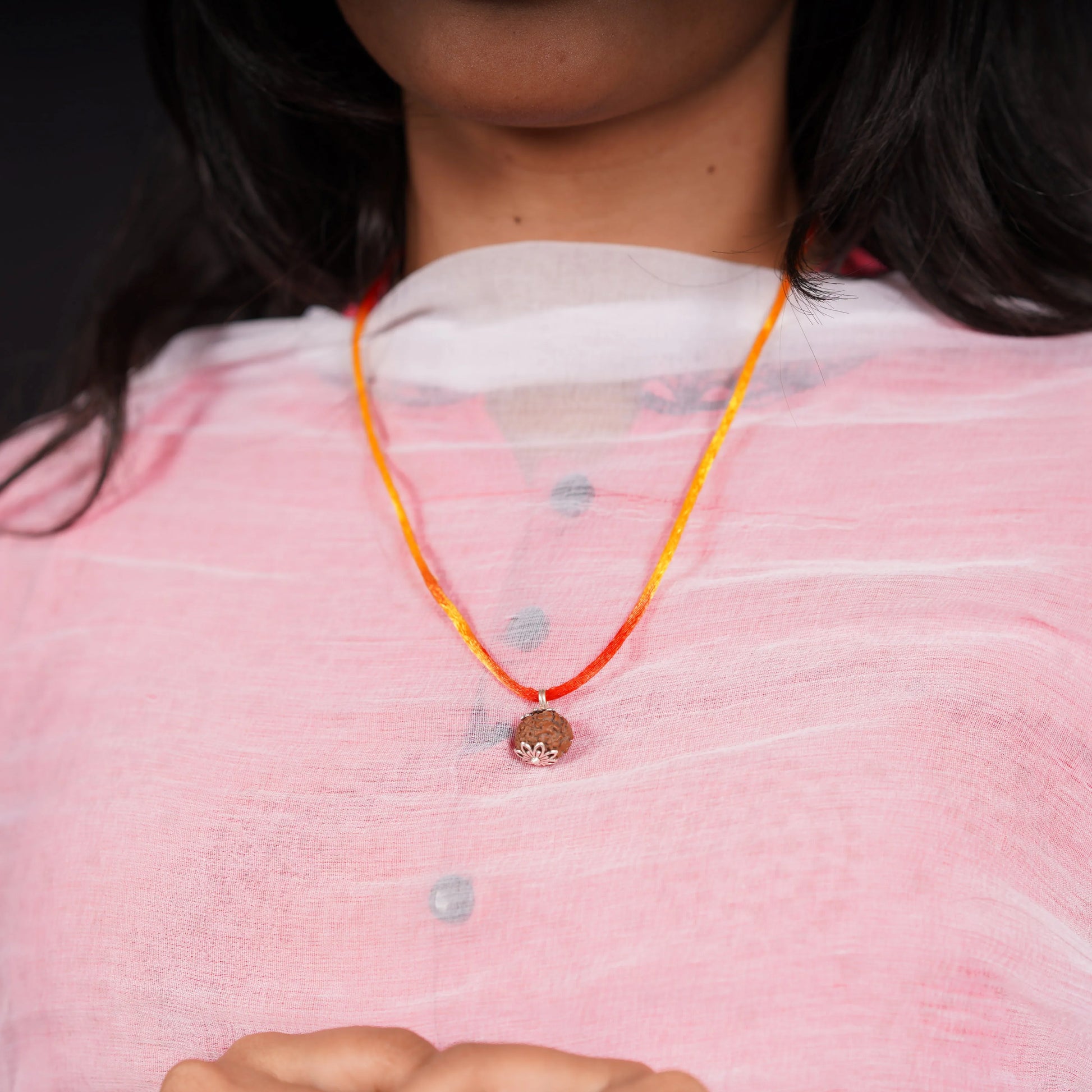 Woman wearing a rudraksha pendant necklace on red-yellow thread over pink kurta
