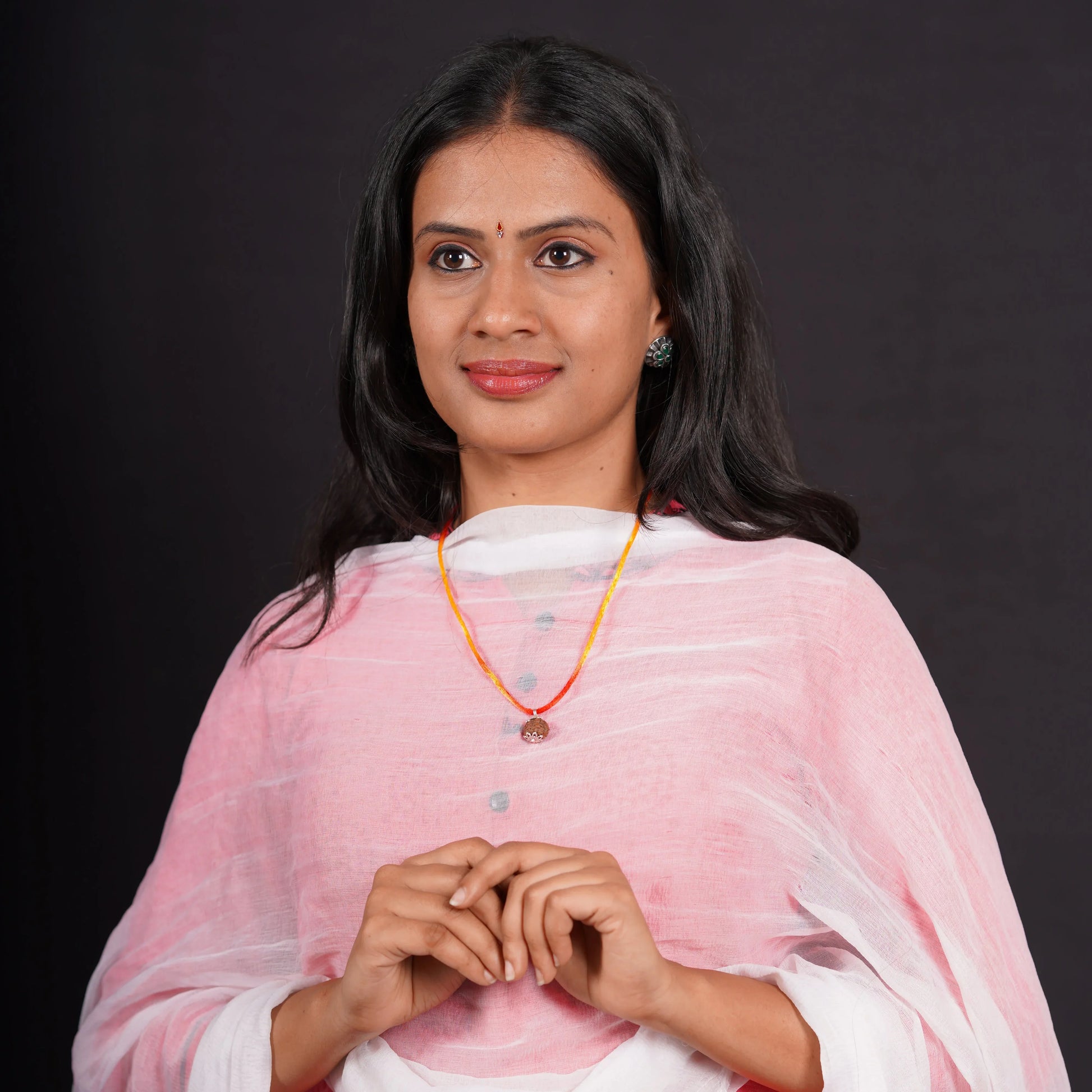 Woman wearing a Rudraksha stone pendant necklace with orange and yellow thread, in pink kurta