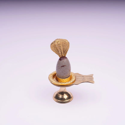 Shiva lingam stone with gold snake stand, Hindu altar decor on white background