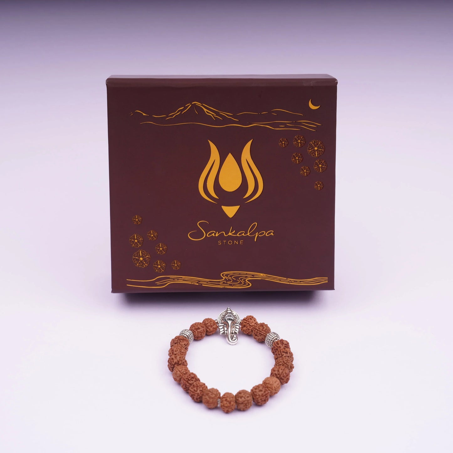 Rudraksha bead bracelet with silver Ganesha charm in front of decorative gift box