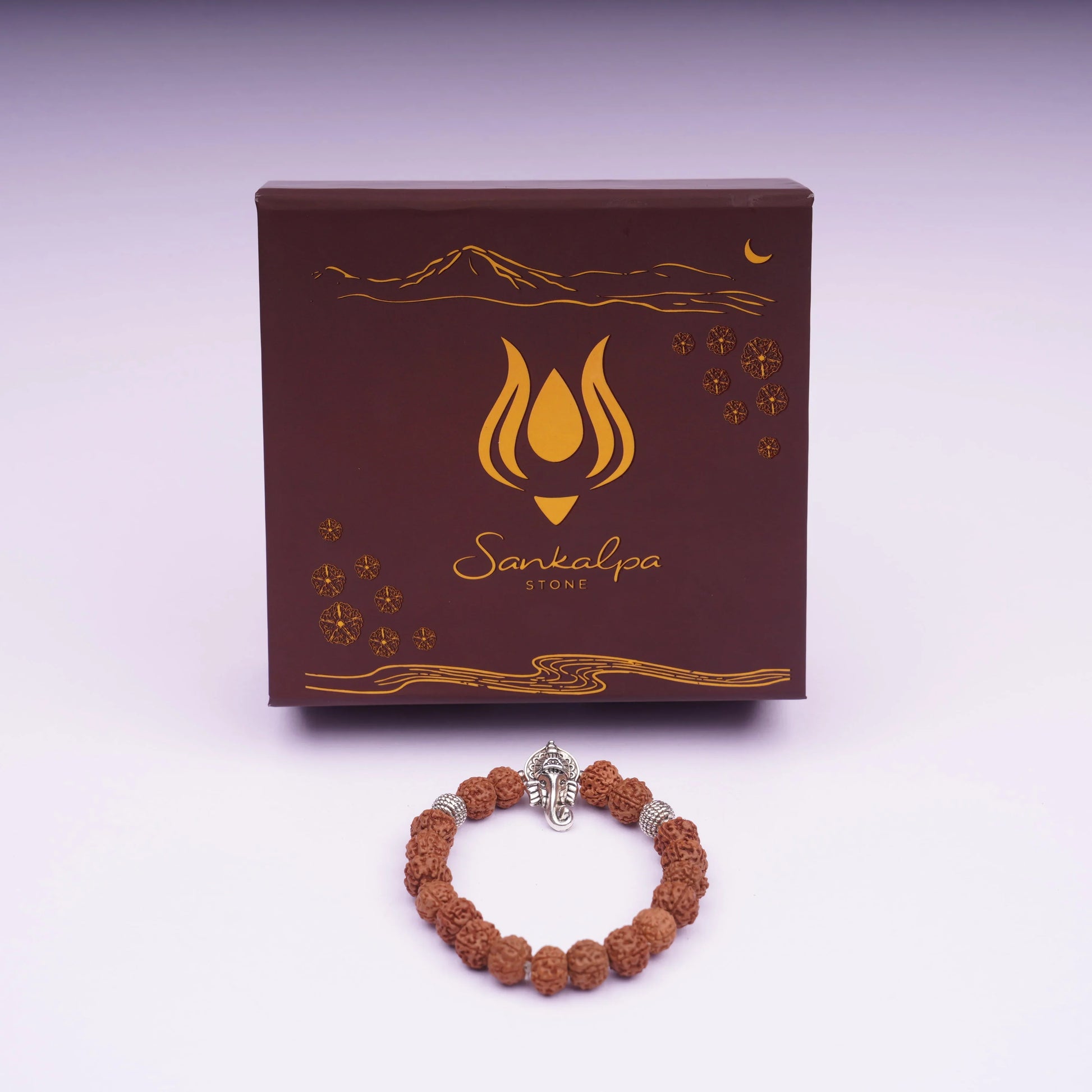 Rudraksha bead bracelet with silver Ganesha charm in front of decorative gift box
