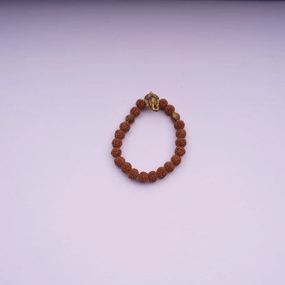 Rudraksha bead bracelet with gold-tone Ganesh charm on light purple background