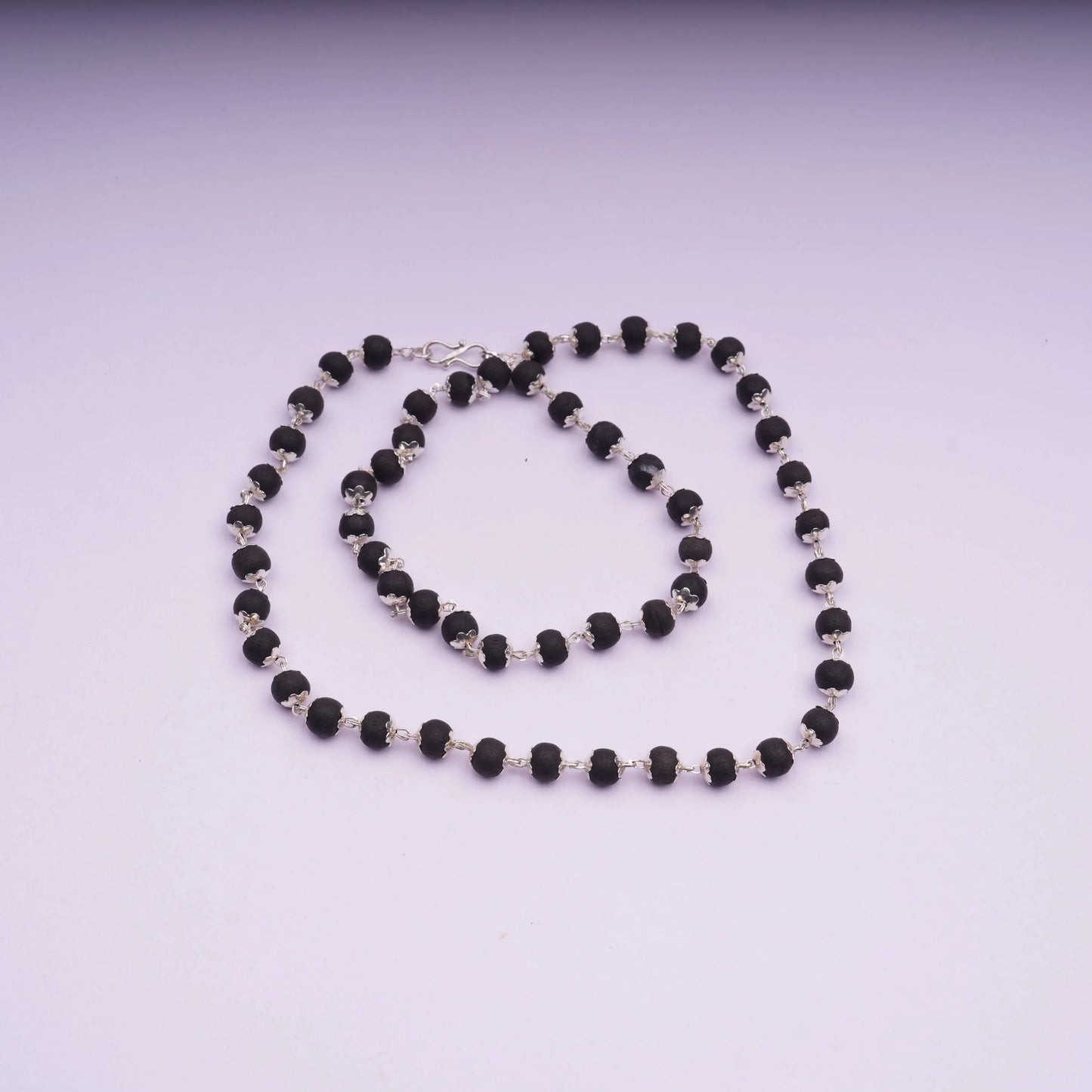 Black bead stone necklace with silver links on a light background