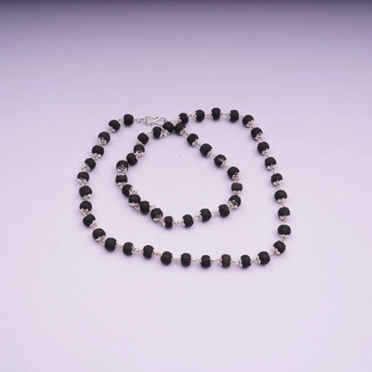 Black bead stone necklace with silver links on a light background