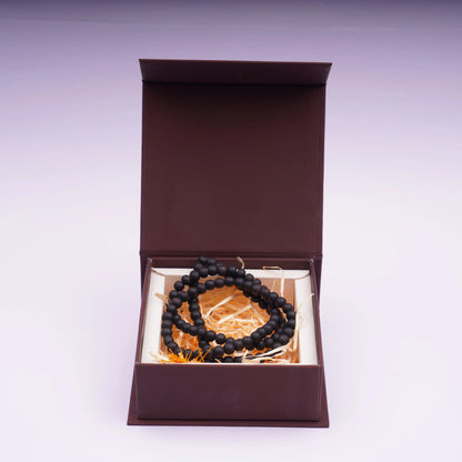 Plain black prayer bead mala in a brown gift box on straw padding