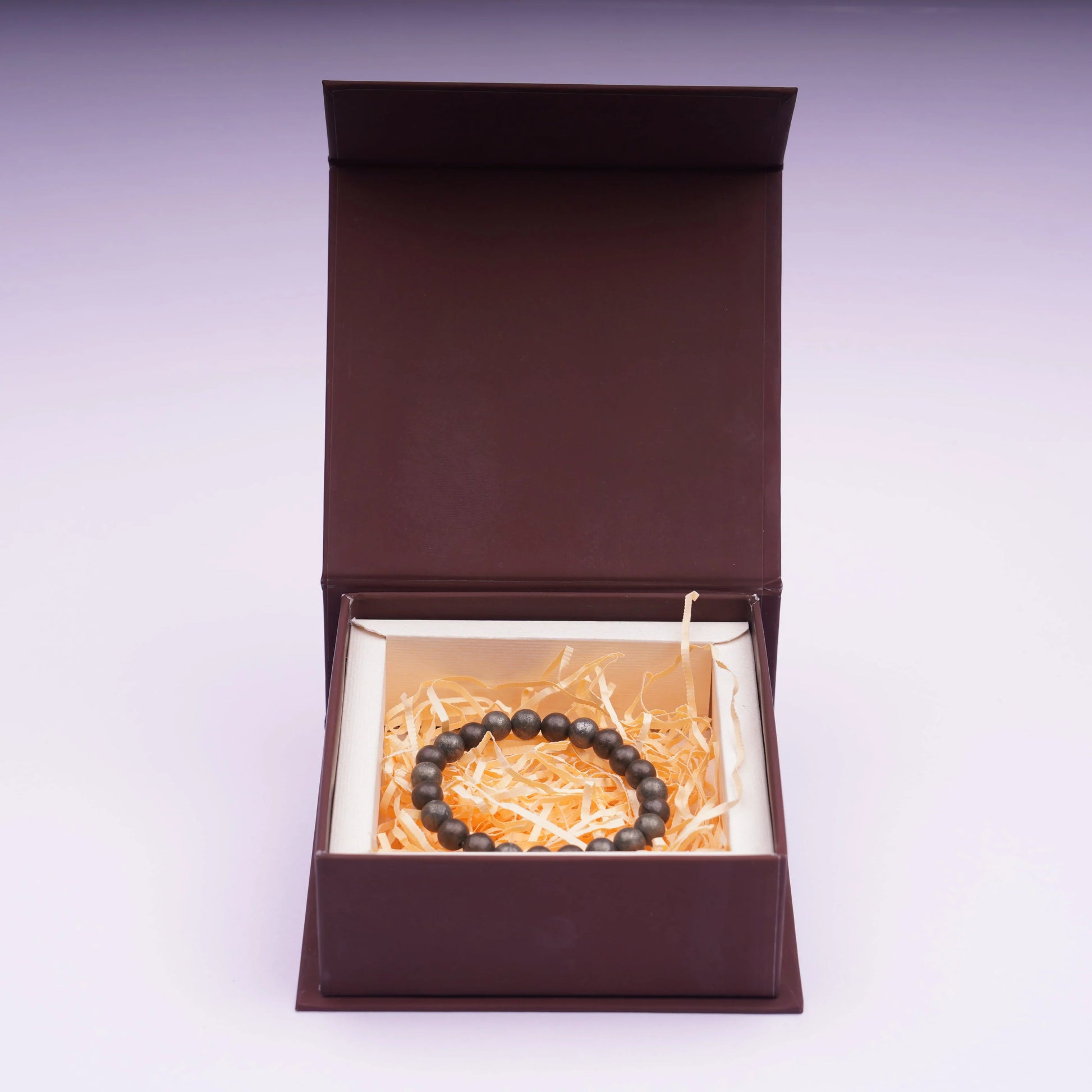 Raw pyrite beaded bracelet in a gift box with shredded paper filling, jewelry product display.