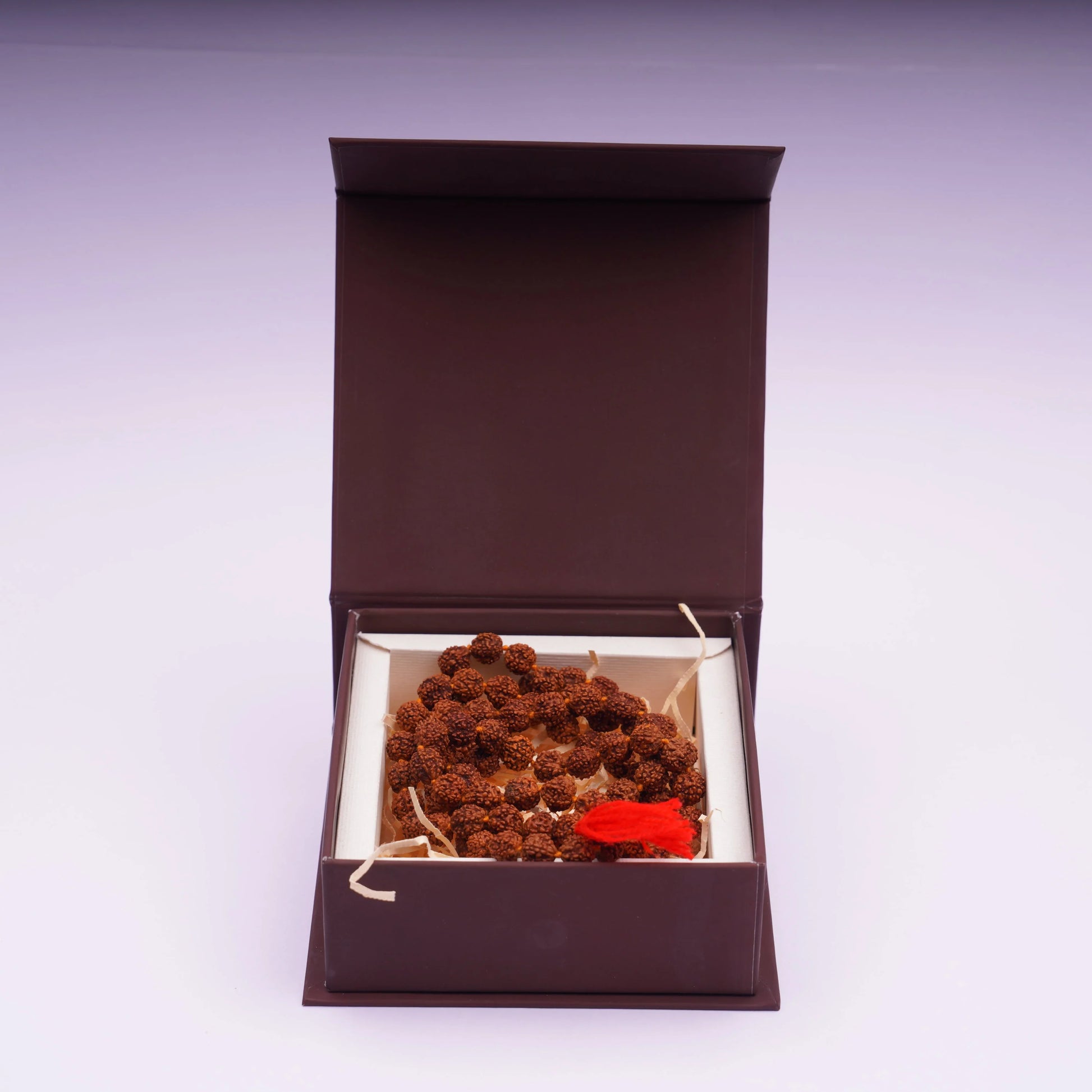 Rudraksha mala prayer beads with red tassel displayed in an open gift box